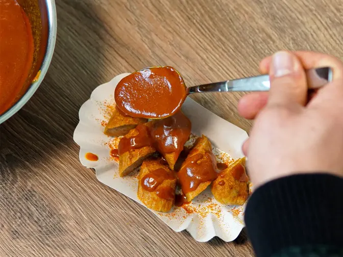 Sombody puts sauce on a currywurst